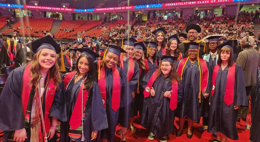 A group of graduates and faculty in their cap and gowns together at commencement